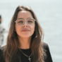 woman in black crew neck t-shirt wearing brown framed eyeglasses standing on rocky shore during